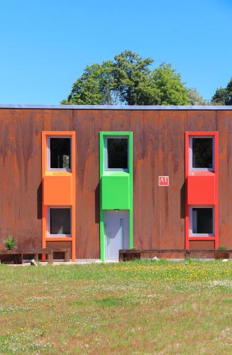 a building with colorful doors and windows in a field at CELTAINER in Maceda