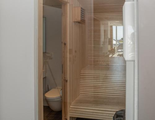 a bathroom with a toilet and a wooden walk in shower at Nordis Apartments in Svolvær