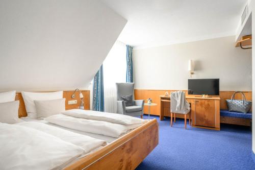 ein Hotelzimmer mit einem Bett und einem Schreibtisch in der Unterkunft Hotel Maier in Friedrichshafen