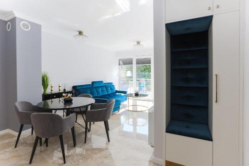 Una sala de estar con una mesa y un sofá azul. en Apartament Szafirowy, en Świnoujście