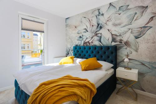 a bedroom with a blue bed with a flower mural on the wall at Apartament Szafirowy in Świnoujście