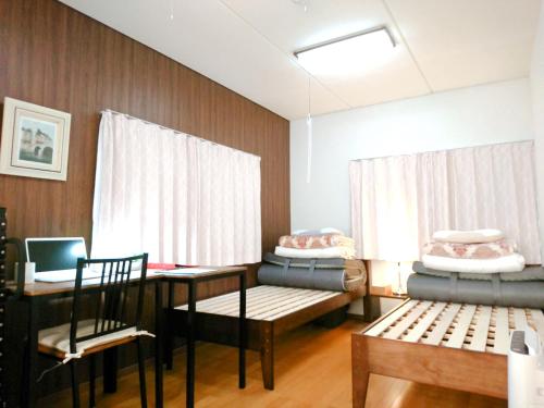 a room with a table and two chairs and a desk at Guesthouse Hajimari in Kashihara