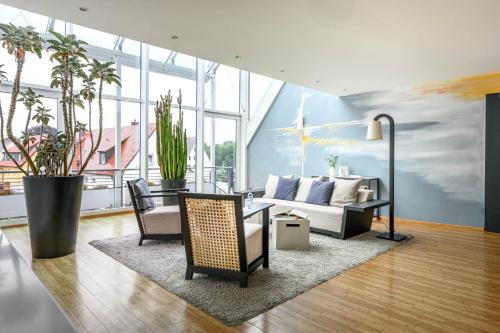 a living room with a couch and chairs and plants at Hotel Maier in Friedrichshafen