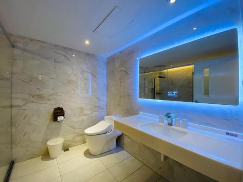 W łazience znajduje się umywalka, toaleta i lustro. w obiekcie Taichung EnrichLife Hotel w mieście Taizhong