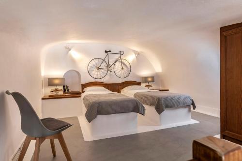 a bedroom with two beds and a bike on the wall at 180° Caldera by Stylish Stays in Firostefani