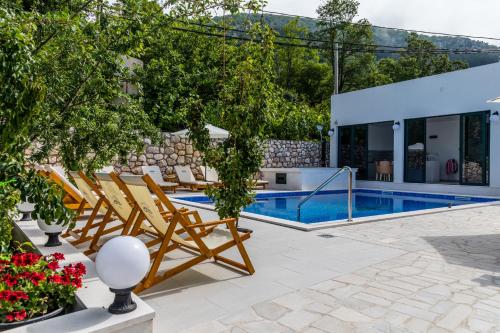 a swimming pool with chairs and a house at Alt Braic Villa in Budva