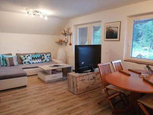 a living room with a couch and a tv and a table at Apartment KAYA in Mojstrana