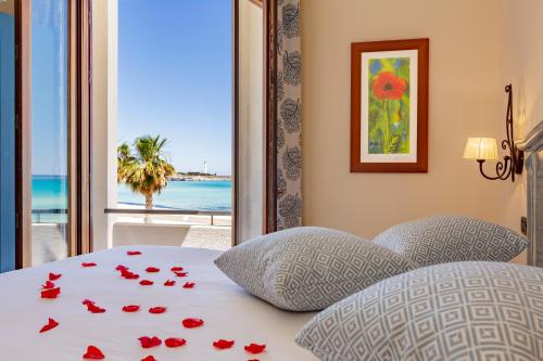 a bedroom with a bed with red rose petals on it at Mira Spiaggia in San Vito lo Capo