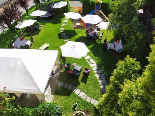 - une vue sur le jardin avec des tables et des parasols dans l'établissement Bed & Breakfast Tiffany, à Domodossola