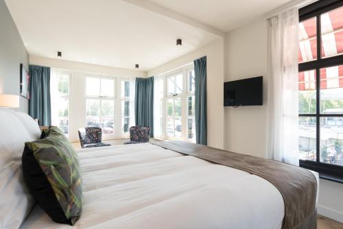 a large bedroom with a large bed with windows at Hof van Holland Hotel in Edam