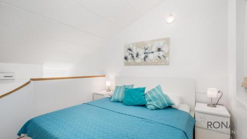 biały pokój z łóżkiem z niebieską pościelą w obiekcie Rona Apartment Flower 1 and Flower 2 w Novalji