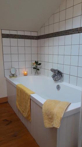 La salle de bains est pourvue d'une baignoire avec des bougies. dans l'établissement countryside lavender cottage, à Saint-Julien-dʼEymet