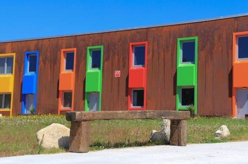 a bench in front of a building with colorful windows at CELTAINER in Maceda