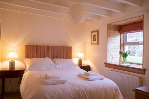 Un dormitorio con una cama blanca con toallas. en Blairchroisk Cottage en Pitlochry