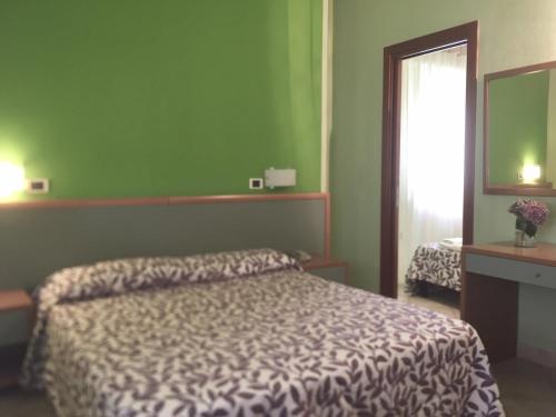 a bedroom with a bed and a green wall at Hotel La Rosa Dei Venti in Albinia