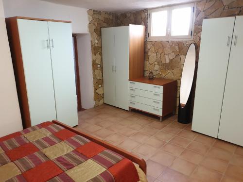 a bedroom with white cabinets and a bed and a stone wall at Casa Vacanze Mistral in Buggerru