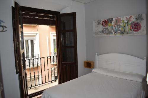 a bedroom with a white bed and a balcony at Pension Castil in Granada
