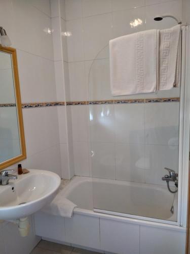 a white bathroom with a tub and a sink at Pension Playa Mar Cachadiñas in Balea