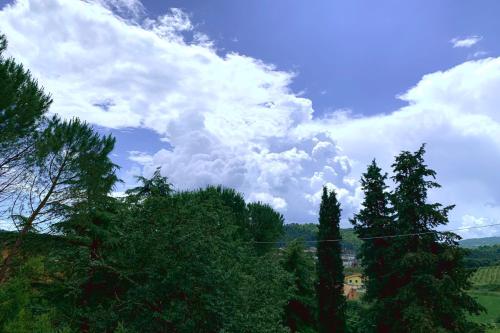 a cloudy sky with trees and a house on a hill at Agriturismo La Collina Toscana in Pieve a Maiano