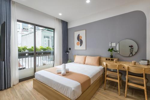 a bedroom with a bed and a table and a desk at Cozrum Homes Ambera House in Ho Chi Minh City