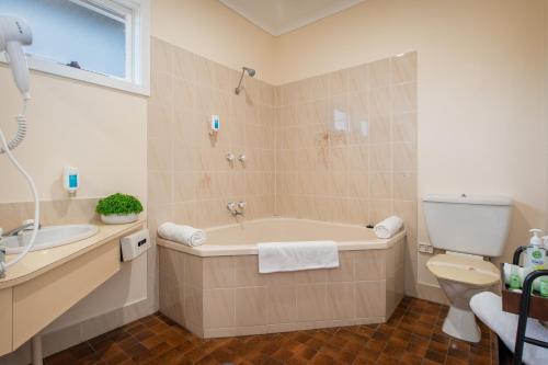 a bathroom with a tub and a toilet and a sink at Australia Park Motel in Albury