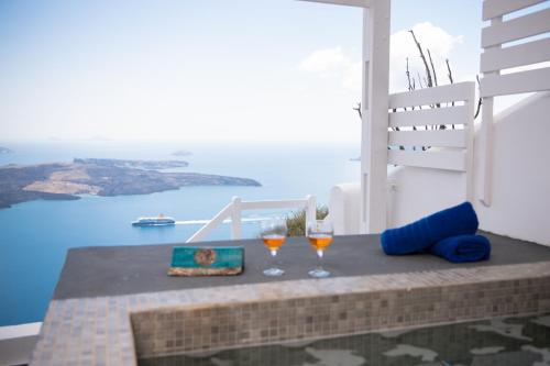 two glasses of wine sitting on top of a table at Iatis View Collection in Imerovigli