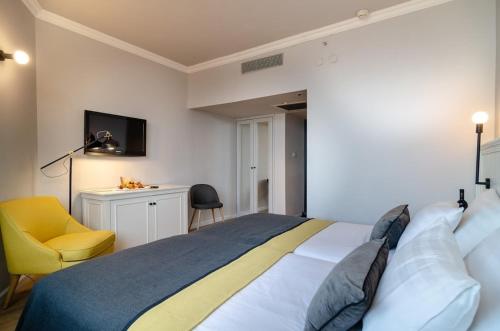 a bedroom with a bed and a yellow chair at Royal Plaza Hotel in Tiberias