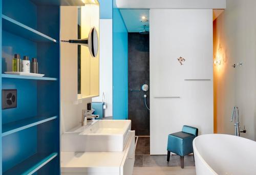 a bathroom with a white sink and a blue wall at Bellevue-Terminus - Urban Lifestyle Hotel in Engelberg