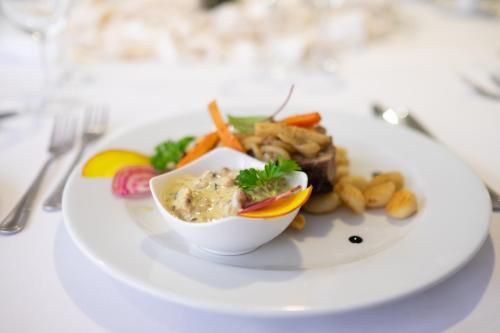 a white plate with a bowl of food on a table at Hotel Wodnik in Slok