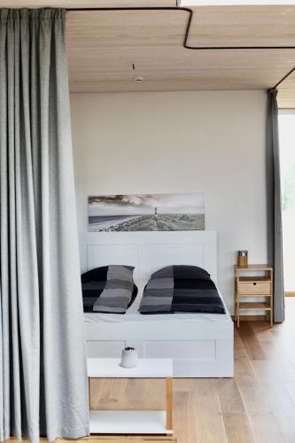 a bedroom with a white bed with two pillows at Jaukus modernios architektūros Svencelės namas in Svencelė