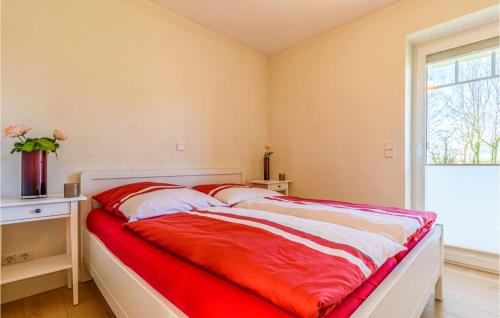 a bedroom with a bed with red sheets and a window at Amazing Apartment In Langenhorn With Kitchen in Langenhorn