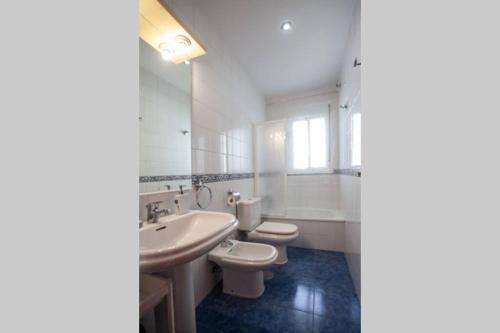 La salle de bains blanche est pourvue d'un lavabo et de toilettes. dans l'établissement Sanlucar Misericordia Centro, à Sanlúcar de Barrameda