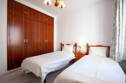 - une chambre avec 2 lits et une armoire en bois dans l'établissement Sanlucar Misericordia Centro, à Sanlúcar de Barrameda