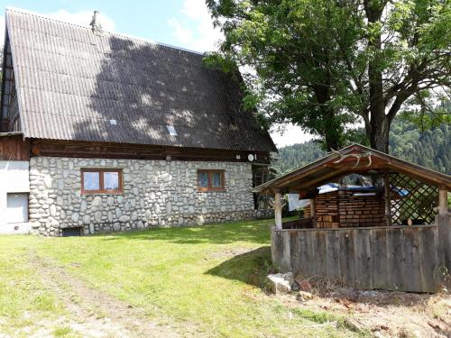 uma casa de pedra com uma árvore e um edifício em Chata pod skalou em Haligovce