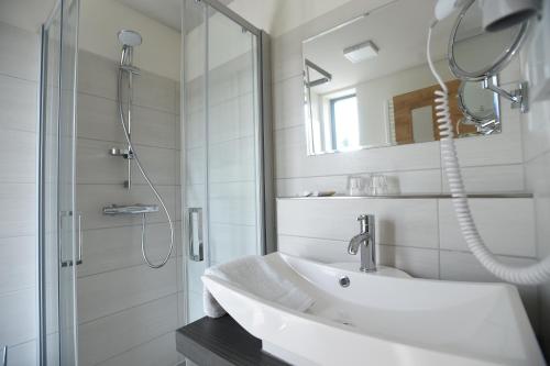 uma casa de banho branca com um lavatório e um chuveiro em Hotel Neue Höhe em Klingenberg