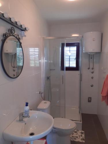 ein Badezimmer mit einem Waschbecken, einem WC und einem Spiegel in der Unterkunft Apartments Lea & Eva in Privlaka