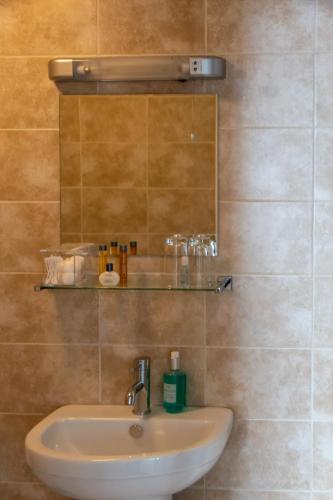 a bathroom with a sink and a mirror at New Steine Hotel - B&B in Brighton & Hove