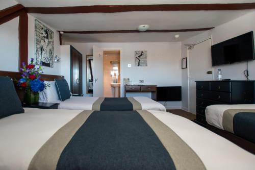 a hotel room with two beds and a television at New Steine Hotel - B&B in Brighton & Hove