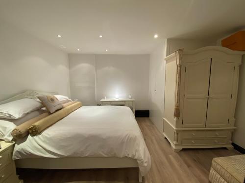 a bedroom with a large white bed and a dresser at Cockfosters executive Mews in Barnet