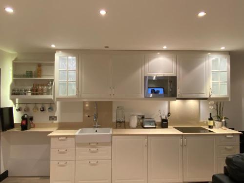 a kitchen with white cabinets and a sink at Cockfosters executive Mews in Barnet