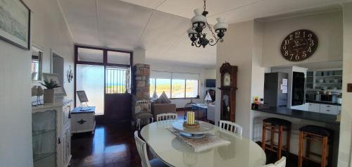 cocina y sala de estar con mesa y reloj en Normandie On Sea en Hermanus