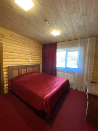 a bedroom with a red bed and a window at Глухомань Аквапарк in Poltava