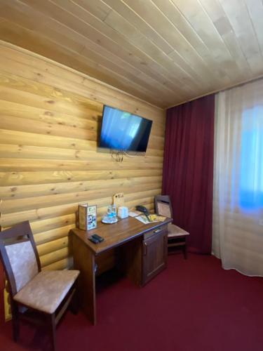 a room with a desk and a television on a wall at Глухомань Аквапарк in Poltava