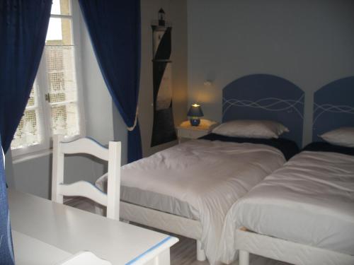 a bedroom with two beds and a table and a window at Les chambres d'hotes du cosquer in Beuzec-Cap-Sizun