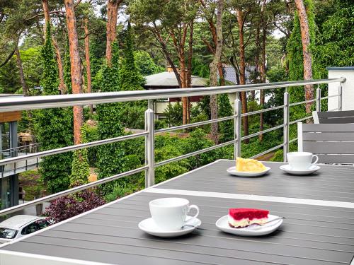 a table with two cups and a slice of cake on a balcony at SPOT JURATA in Jurata
