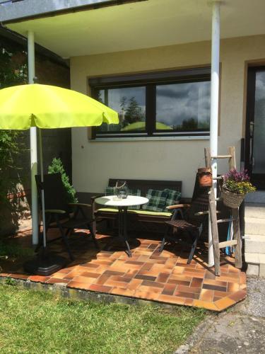 un patio con una mesa y una sombrilla amarilla en Ferienwohnung Karola, en Bad Bocklet