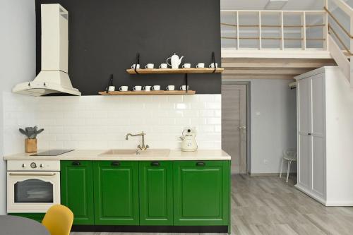 a green kitchen with a sink and a stove at Przystań Twórców in Słupsk