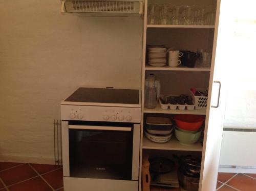 a kitchen with a stove and a shelf with dishes at Tversted Apartment in Tversted