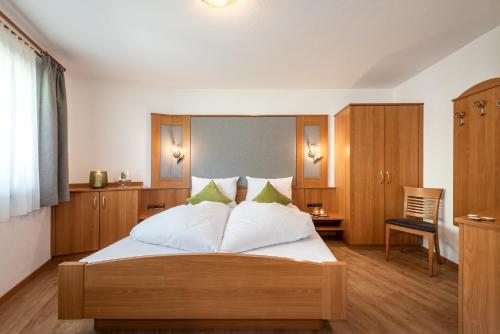 a bedroom with a bed with white sheets and green pillows at AlpenChalet Niederkofler in San Giovanni in Val Aurina