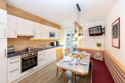 a kitchen with white cabinets and a table with food on it at Elto Appartements in Kaprun